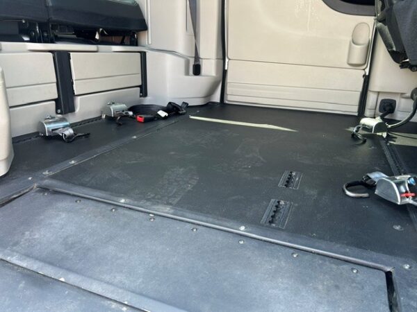 Truck cargo area with a black rubber floor, side tie-down anchors, and latches along the walls.