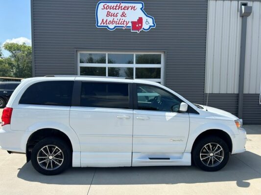 White passenger minivan with tinted windows parked in front of a gray building with a 'Southern Bus & Mobility' sign above the entrance,