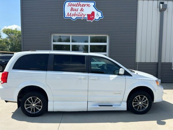 White passenger minivan with tinted windows parked in front of a gray building with a 'Southern Bus & Mobility' sign above the entrance,
