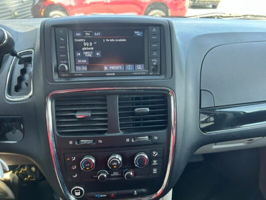 Car dashboard center console with a touchscreen radio display, two air vents, and climate control knobs.