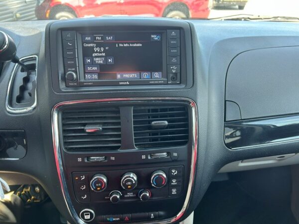 Car dashboard center console with a touchscreen radio display, two air vents, and climate control knobs.
