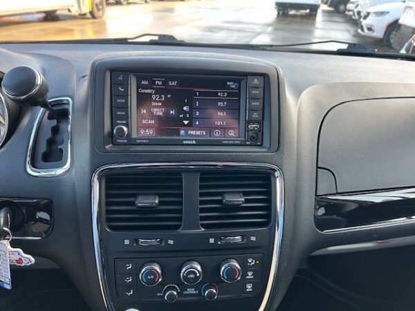 Radio, AC Car dashboard with a touchscreen infotainment system displaying radio presets and time, surrounded by climate controls and vents at center console
