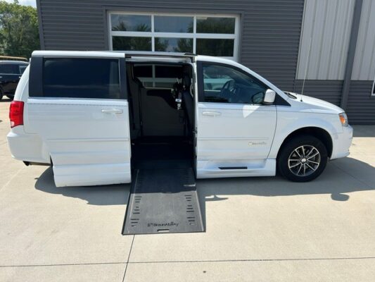 White wheelchair-accessible minivan with a side-entry ramp extended for loading a wheelchair.