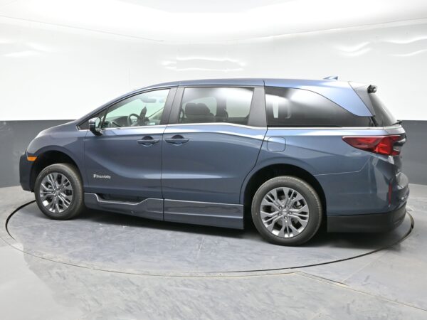 004 Blue minivan shown from the side in a studio setting, revealing front and rear doors and alloy wheels, BraunAbility branding on the lower front door panel