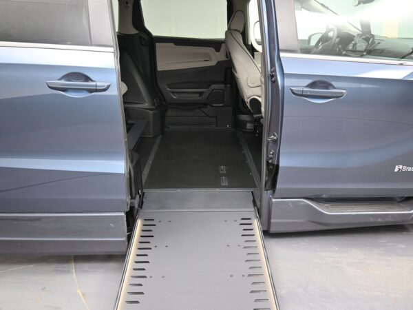 011 Blue van with wheelchair ramp extended, sliding door open, showing gray interior and driver's area.