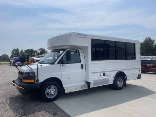 White Class C motorhome bus with a raised cab and large dark windows, parked in a lot