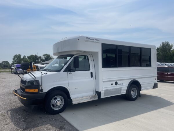 White Class C motorhome bus with a raised cab and large dark windows, parked in a lot