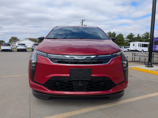 Front view of a red SUV parked in a lot, with other cars and a cloudy sky in the background.