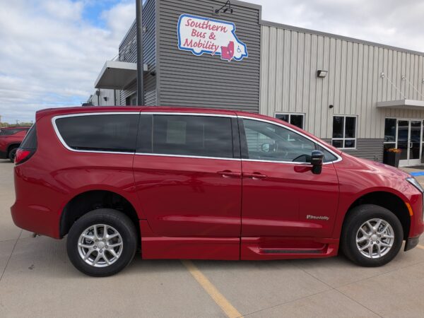 Red BraunAbility minivan in a parking lot in front of a gray metal building with a 'Southern Bus & Mobility' sign.
