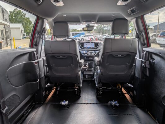 Car interior viewed from the rear cargo area toward the front seats, with a central touchscreen on the dashboard visible.