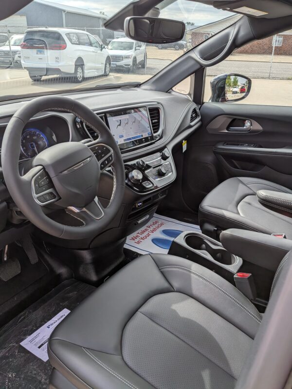 Interior of a modern SUV: steering wheel, center touchscreen, and gray leather seats with white stitching; dashboard controls visible.
