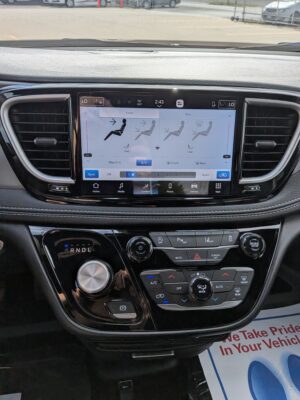 In-car center console with a large touchscreen showing climate controls and vents surrounding it, gear shifter visible below