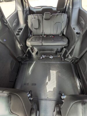 Two black leather rear captain seats with headrests and visible seat belts in a vehicle interior, cup holders on the side panels behind them