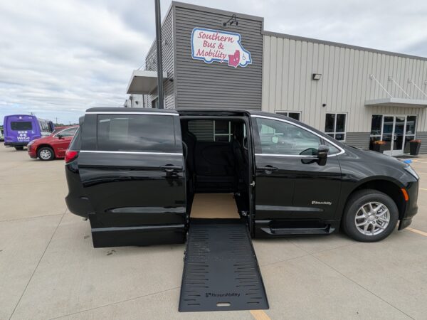 PXL_20260922_201311180 Black BraunAbility wheelchair-accessible van with its side ramp deployed in a parking lot in front of a Southern Bus & Mobility building.