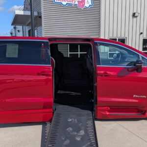 Red wheelchair-accessible minivan with a lowered ramp extended for boarding at a dealership