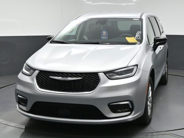 wav-2C4RC1BG3RR138911-1 Front three-quarter view of a silver Chrysler minivan in a showroom, showing the glossy grille and headlights.