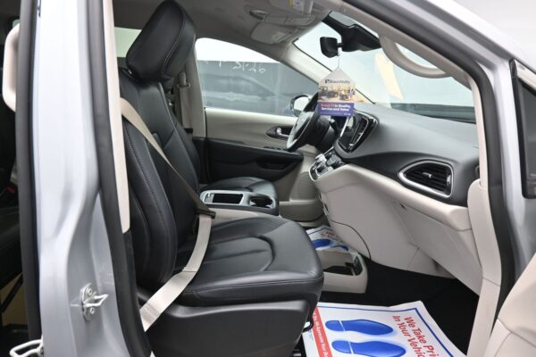 Open car door reveals the front passenger area of a modern SUV with black leather seats, center console, and a hanging dealership tag.