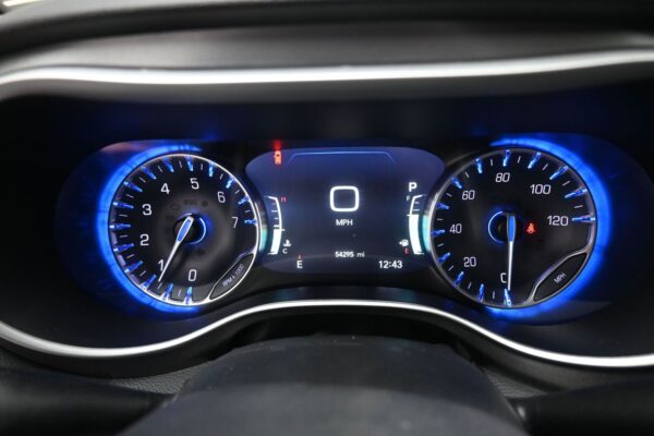 Digital dashboard showing current speed 0 MPH with blue-illuminated gauges on left tachometer and right speedometer; center display shows P gear, 0 mph, 54295 miles, and time 12:43, with warning indicators faintly visible.