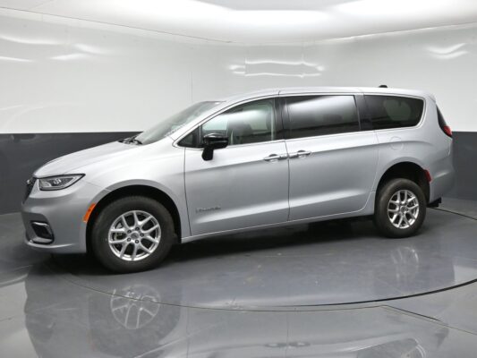 Silver minivan in a studio, side view with sliding doors and alloy wheels are visible.