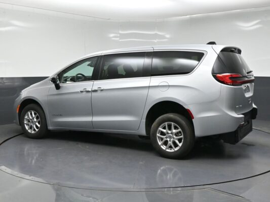 Silver minivan shown in a studio setting, side profile view with front door and rear hatch visible on a turntable platform, indoors.