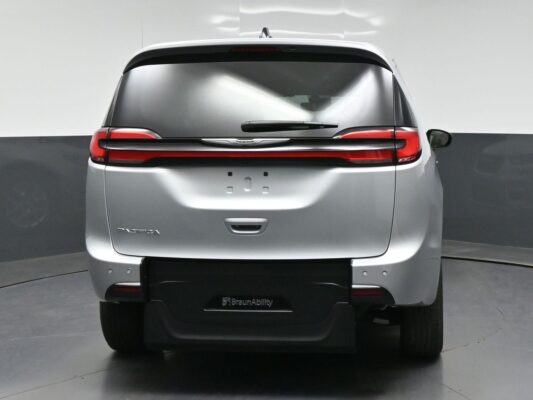Rear view of a silver Chrysler Pacifica minivan with BraunAbility branding on the bumper and dark rear window in a studio setting.