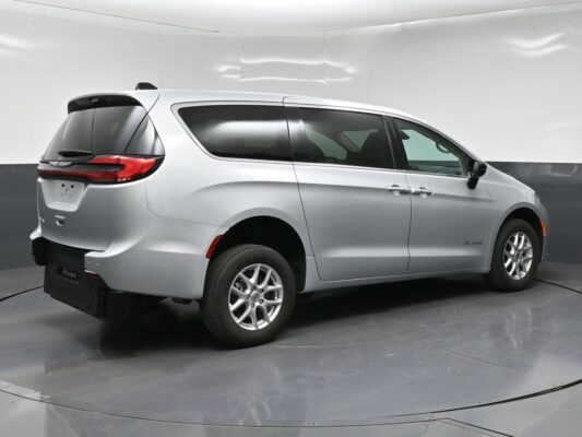 Silver Chrysler Pacifica minivan rear three-quarter view in a studio setting with tinted windows and bespoked lighting.
