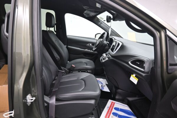Interior of a black car showing the driver and front passenger seats with seat belts and a central dashboard.