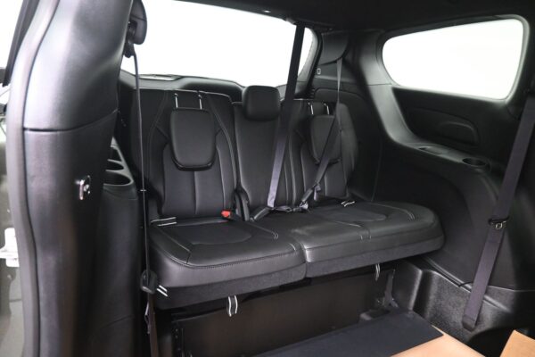 Black leather backseat area of a SUV with three seating positions and visible seatbelts (two shoulder belts and a center belt).