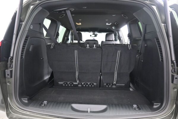SUV rear interior with hatch open; third-row seats upright and secured, creating a small cargo area