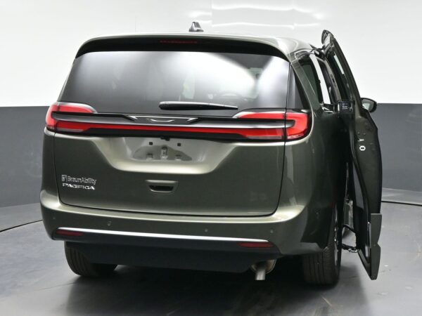 wav-2C4RC1BG7VR577944-5 Rear view of a BraunAbility Pacifica mobility van with the side-entry door open on the right; red tail lights and gray body visible