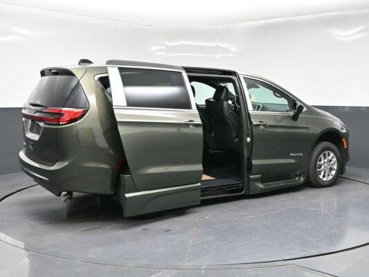 Gray mobility minivan with the side door open and a lowered ramp for wheelchair access, BraunAbility-equipped.