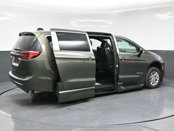 wav-2C4RC1BG7VR577944-6 Gray mobility minivan with the side door open and a lowered ramp for wheelchair access, BraunAbility-equipped.