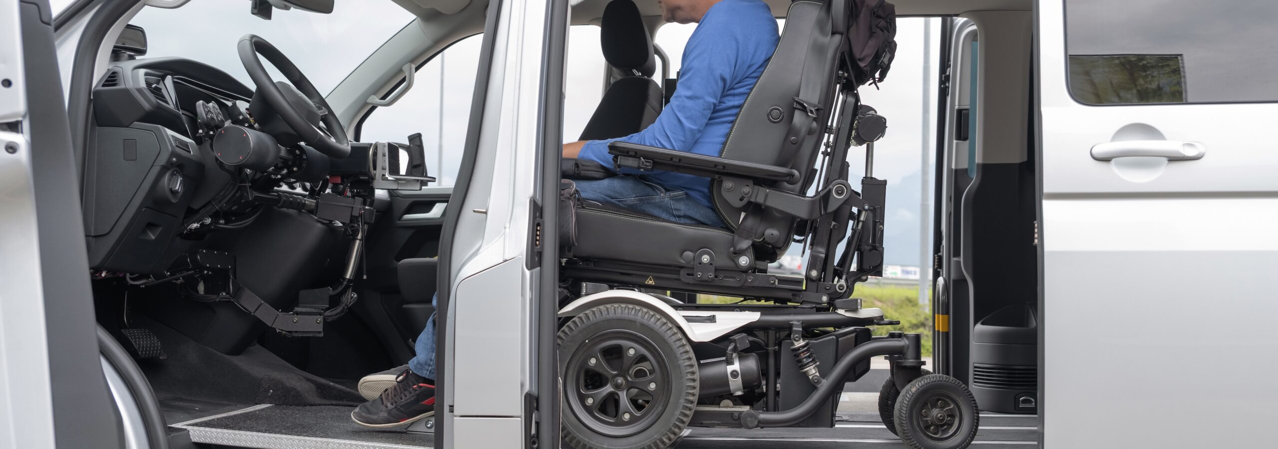 Wheelchair user preparing to drive directly from a powered wheelchair inside an adapted van designed for independent mobility.