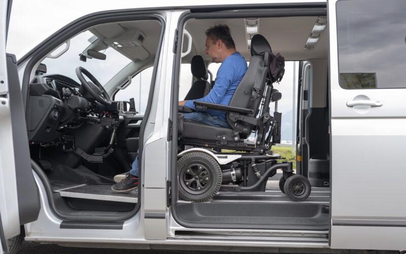 Wheelchair user preparing to drive directly from a powered wheelchair inside an adapted van designed for independent mobility.