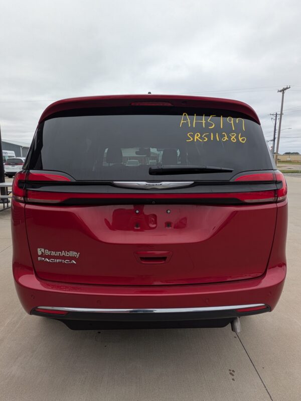 PXL_20260922_161038815 Rear view of a red Chrysler Pacifica BraunAbility minivan with yellow inventory numbers written on the rear window (AH5197, SR511286).