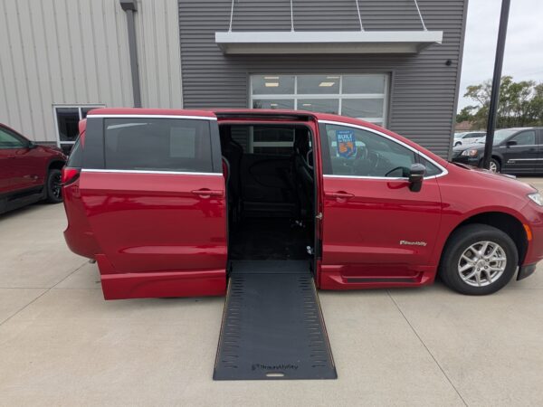 PXL_20260922_161104848 Red BraunAbility minivan with a lowered ramp extended to the ground in a dealership parking lot.
