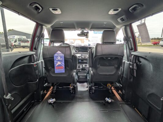 Interior of a wheelchair-accessible van with rear seats removed, revealing a flat, clear floor and wheelchair tracks along the sides.