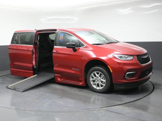 Red wheelchair-accessible minivan with the side door open and ramp extended.